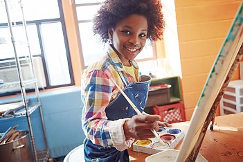 young girl smiling and painting in an art class funded by HAVlife